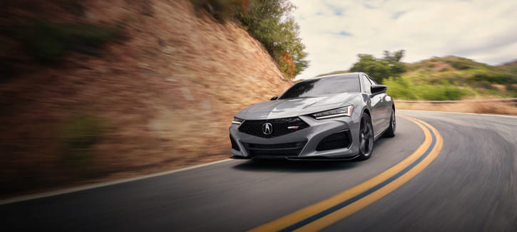 A gray Acura TLX driving on a winding road.