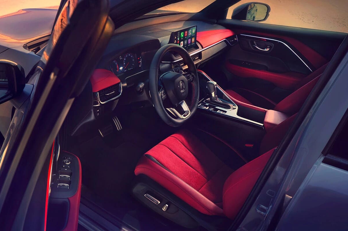 Sleek 2026 Acura ADX interior with bold red and black seats, digital dashboard, and touchscreen displaying apps, exuding a modern and sporty vibe.