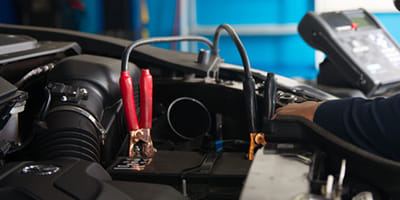 Mechanic performing battery check on a vehicle