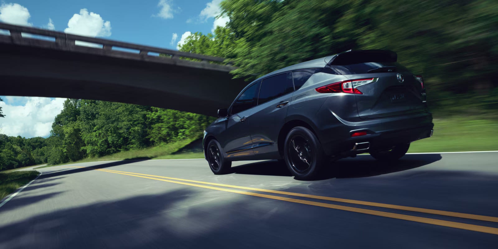 A sleek 2026 Acura RDX driving dynamically on a scenic road, showcasing its athletic stance.