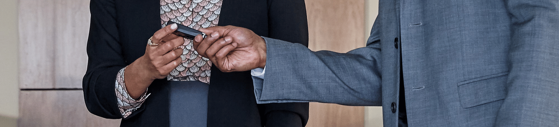 Two business professionals in formal attire exchange a car keys, suggesting a business agreement.