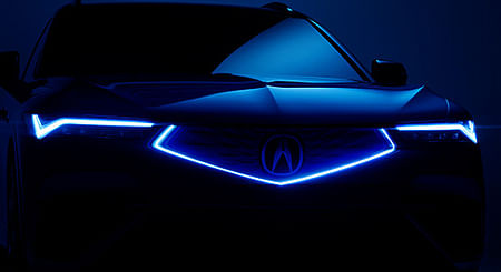 Front view of a blue ZDX with lights on.