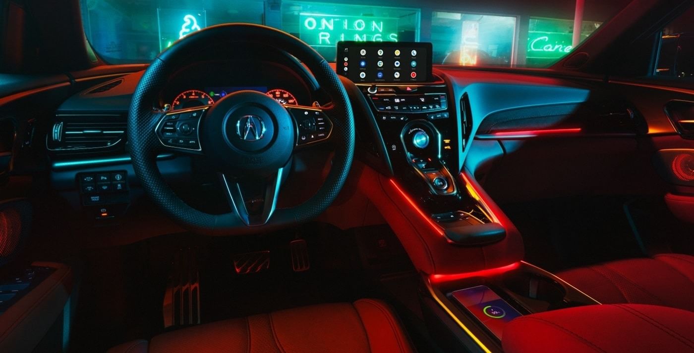 Stylish 2025 Acura RDX interior with a modern dashboard, illuminated controls, and a high-tech display, set against vibrant neon lighting.