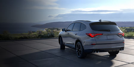 A silver 2026 MDX parked on a coastal hillside, overlooking a panoramic seascape.