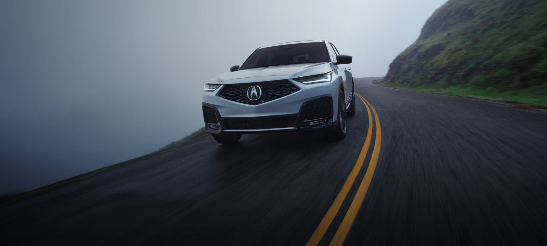 A 2025 Acura MDX in motion, showcasing its powerful V6 performance and dynamic handling on a scenic road.
