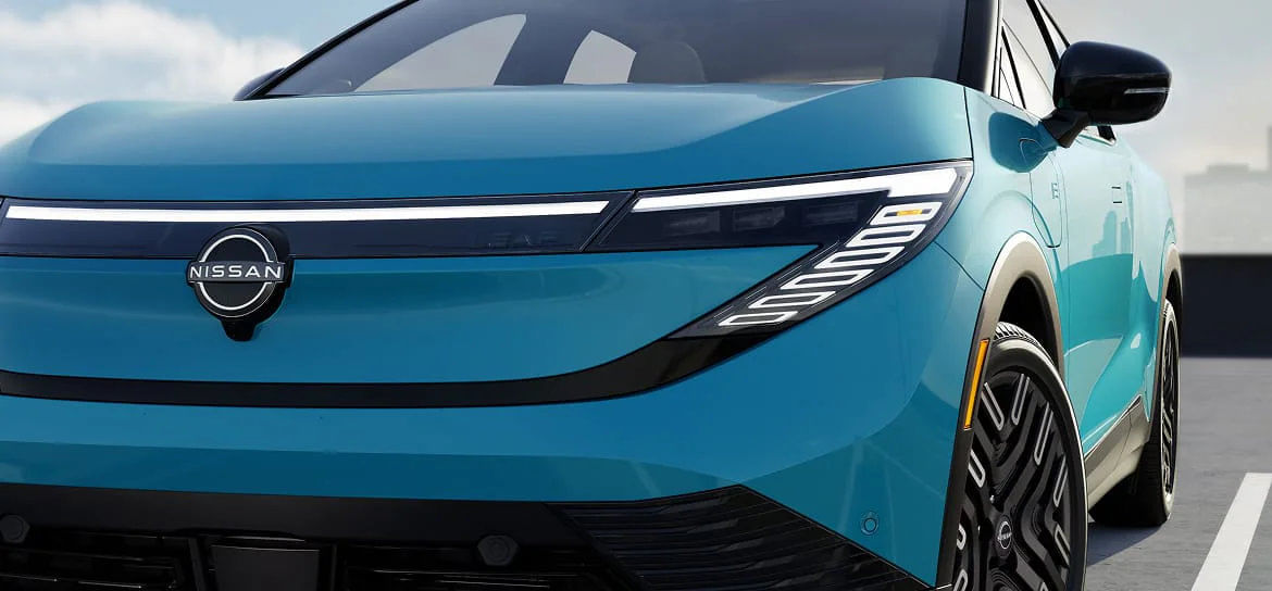 A close-up of the 2026 Nissan Leaf's seamlessly integrated LED signature headlights and V-Motion grille.