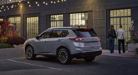 2026 Rogue parked in front of the retail store front, with a couple walking toward the entrance.