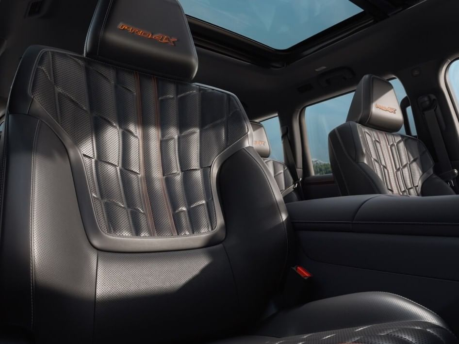 Interior view of a 2026 Nissan Armada showcasing sleek black leather seats with diamond-patterned stitching and orange accents, under a sunroof.
