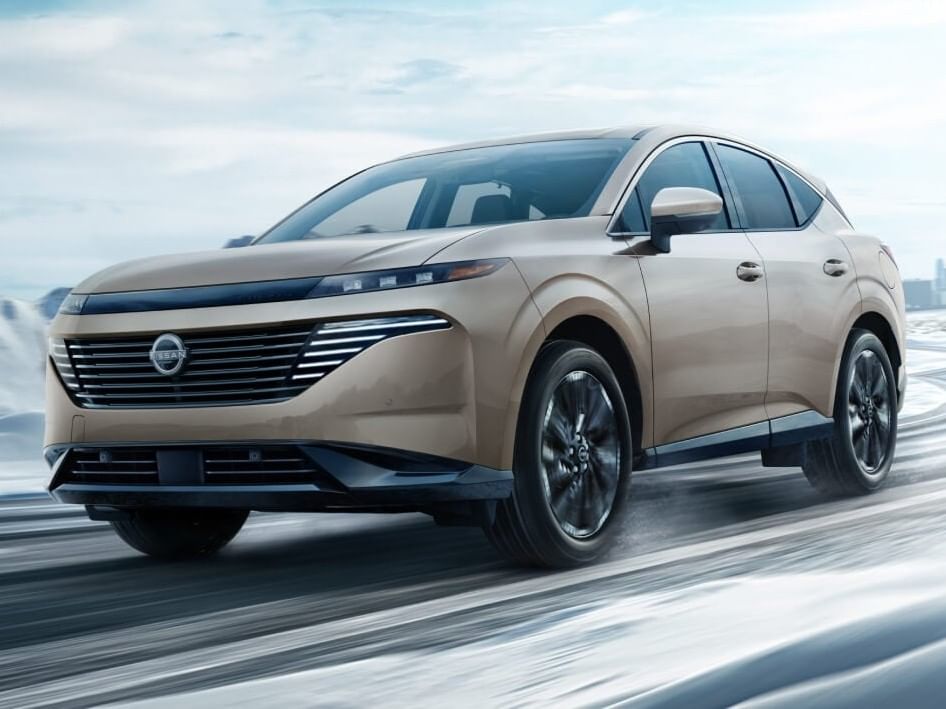A sleek beige 2026 Nissan Murano drives on a snowy road, showcasing its modern design and advanced features in a winter setting.