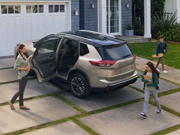 A woman and two kids pose next to a stylish 2026 Nissan Rogue, highlighting its versatility and family-friendly features.