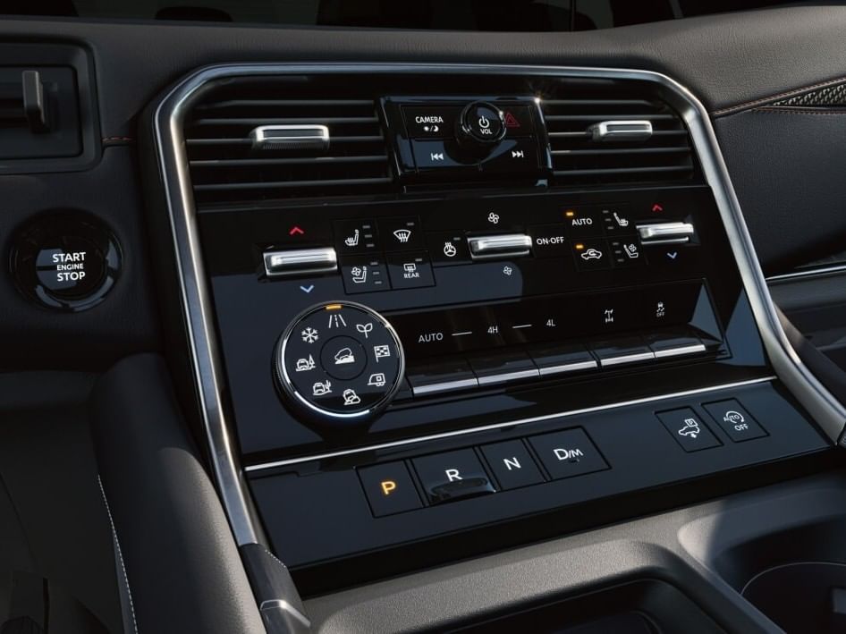 Close-up of a 2026 Nissan Armada dashboard interface featuring controls for climate, audio, gear shift, and engine start/stop button.