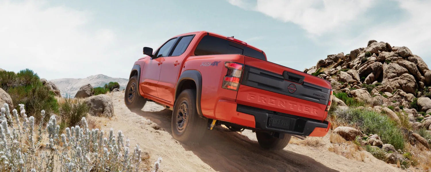 The 2026 Nissan Frontier navigating a rugged mountain trail, demonstrating its legendary 4x4 capability.