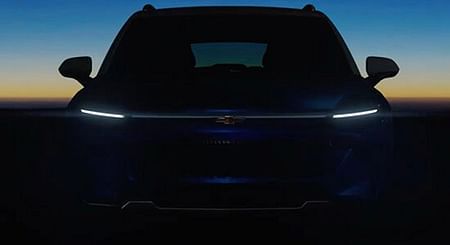 A front end of a navy Chevrolet Equinox with lights on.