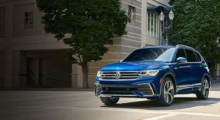 A blue Tiguan driving through a city street.