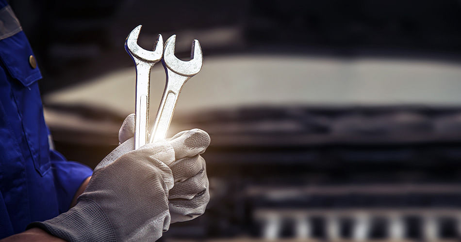 Close-up of mechanic's gloved hands holding two wrenches