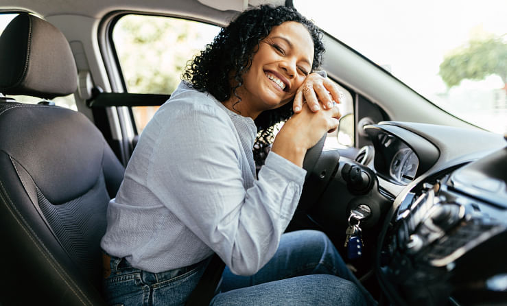 Woman laying on the steering wheel of their purchased vehicle