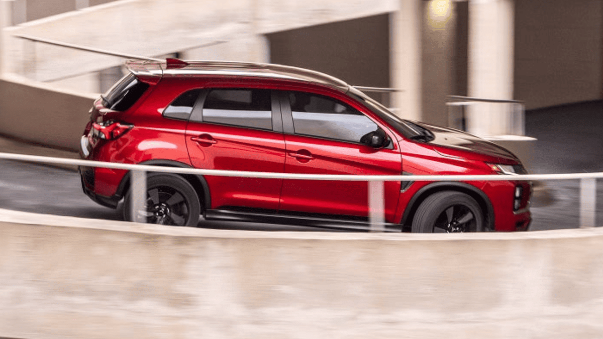 Side profile of a red 2025 Mitsubishi Outlander Sport near Valrico, FL, driving down a spiral parking ramp