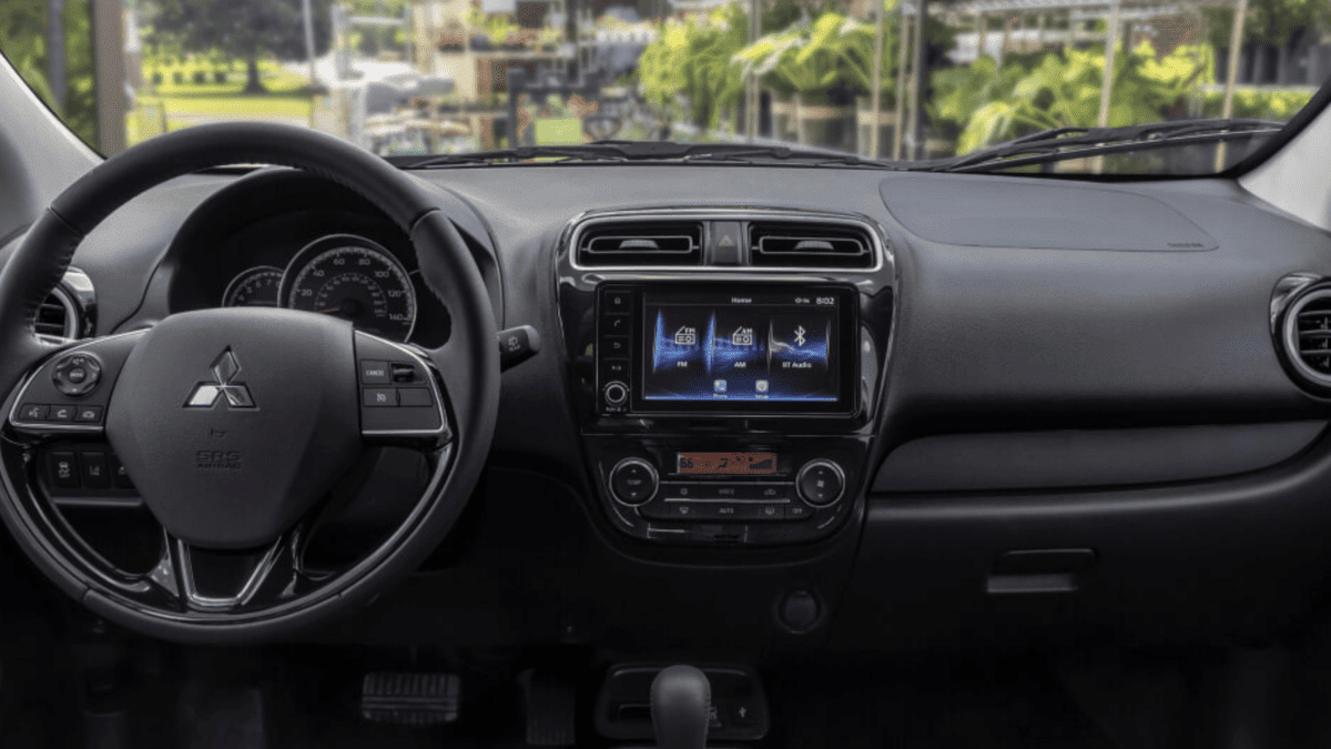 Interior dashboard of the 2024 Mitsubishi Mirage, showcasing the infotainment screen, climate controls, and steering wheel with mounted controls, emphasizing a tech-forward yet compact design.