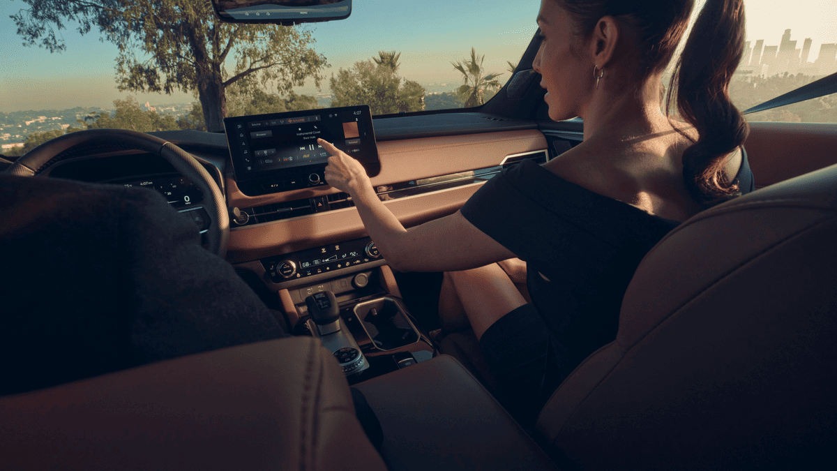 Woman interacting with the touchscreen infotainment system in the 2025 Mitsubishi Outlander near Tampa, FL, highlighting its tech-savvy cabin and scenic city view.