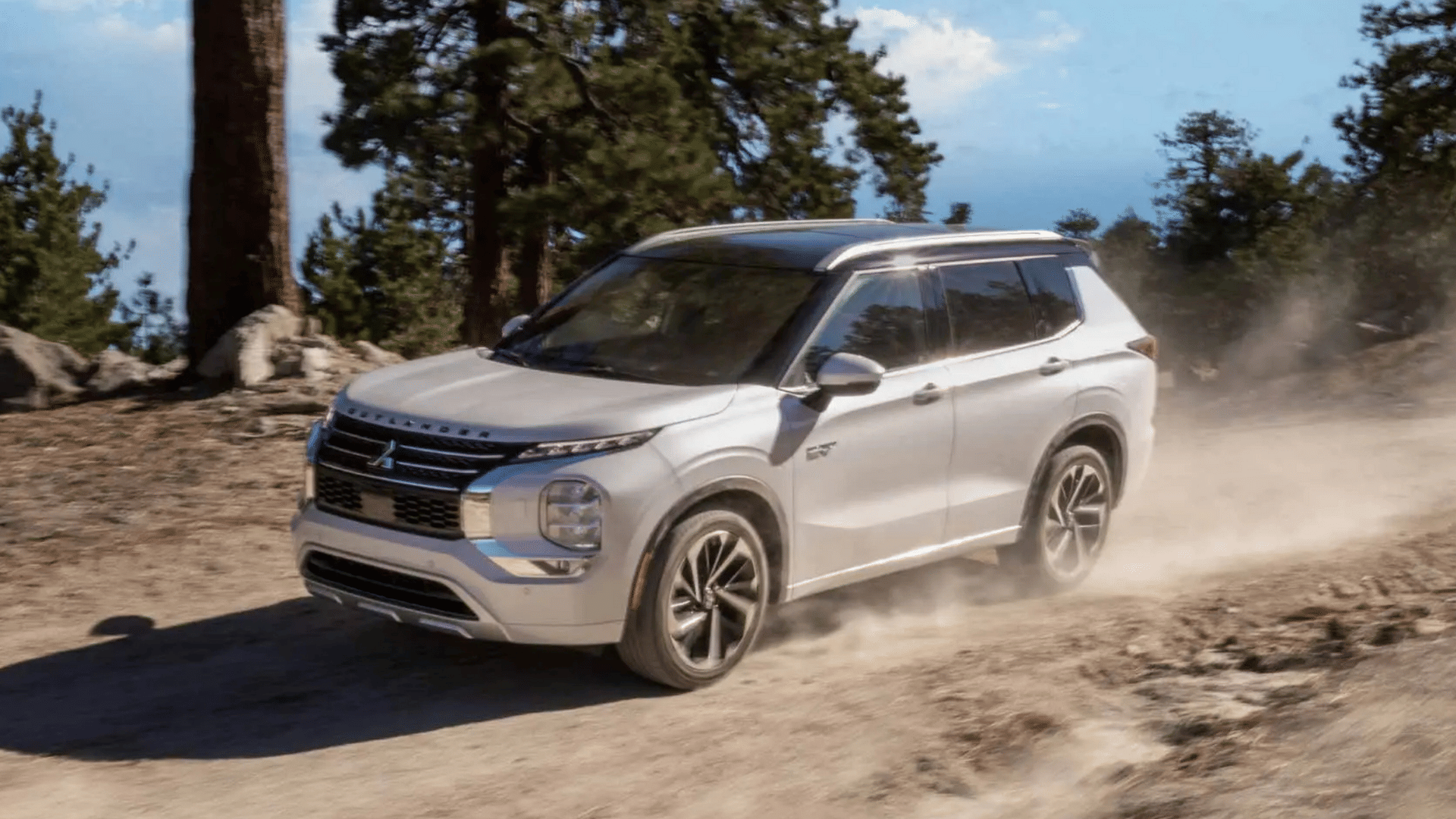 2025 Mitsubishi Outlander PHEV photographed in the mountains near Lakeland, FL, kicking up dust to highlight its rugged plug-in hybrid power.