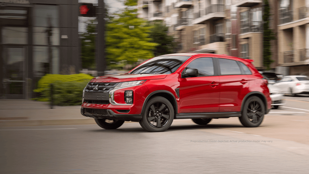 Side view of a red 2024 Mitsubishi Outlander Sport navigating a parking garage ramp near Tampa, FL, showing sleek urban design