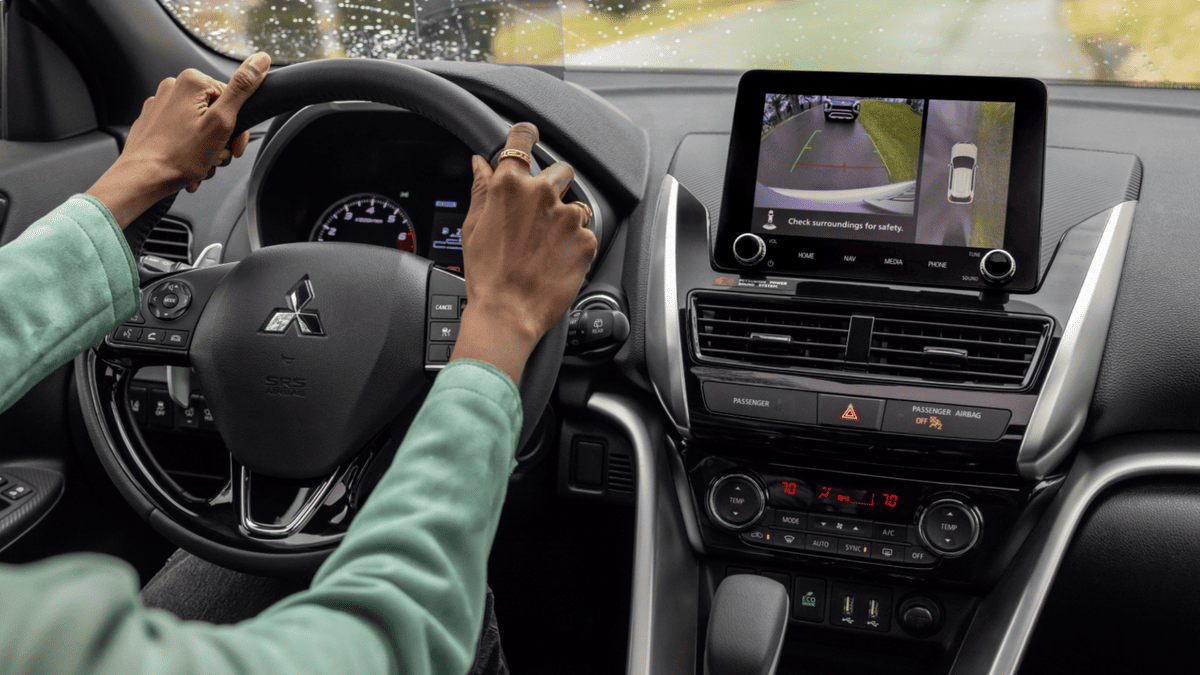 Interior of the 2025 Mitsubishi Eclipse Cross near Tampa, FL, highlighting the touchscreen display with backup camera and steering wheel controls in use.