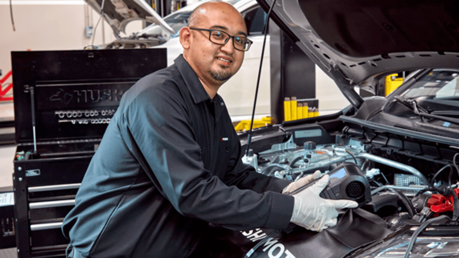  Mitsubishi service specialist pouring engine oil during a maintenance check near Lakeland, FL.