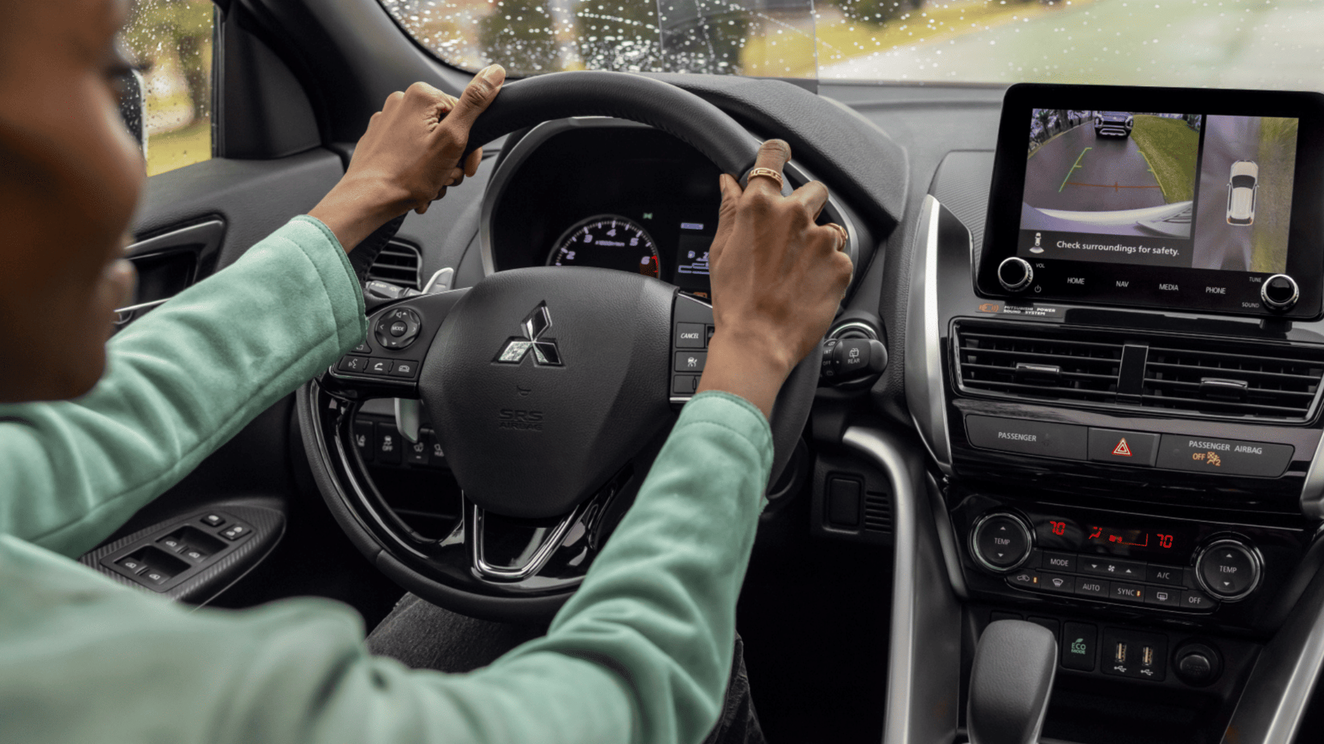 2025 Eclipse Cross interior view with driver using steering wheel and backup camera