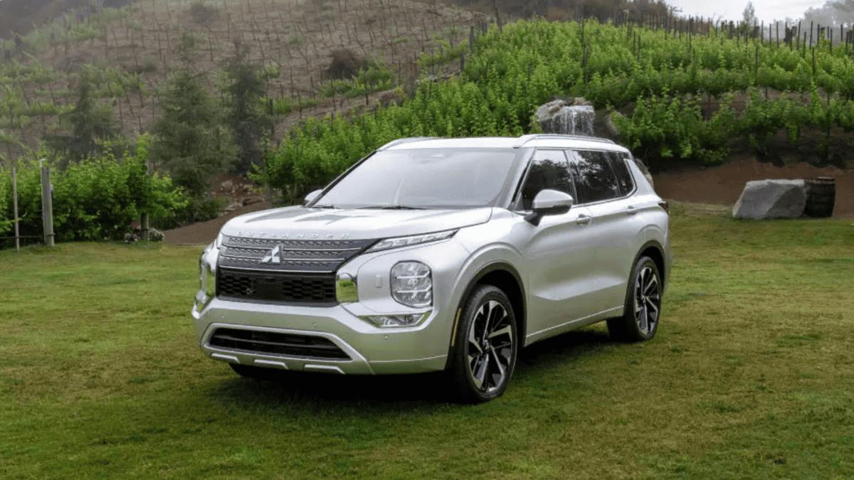 Front view of the 2024 Mitsubishi Outlander parked on grass near Tampa, FL, highlighting its modern grille and sleek SUV design.