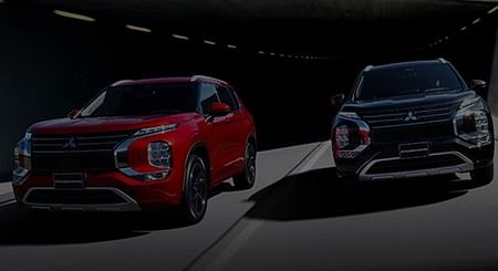 A red and black 2024 Outlander SUV driving side by side.