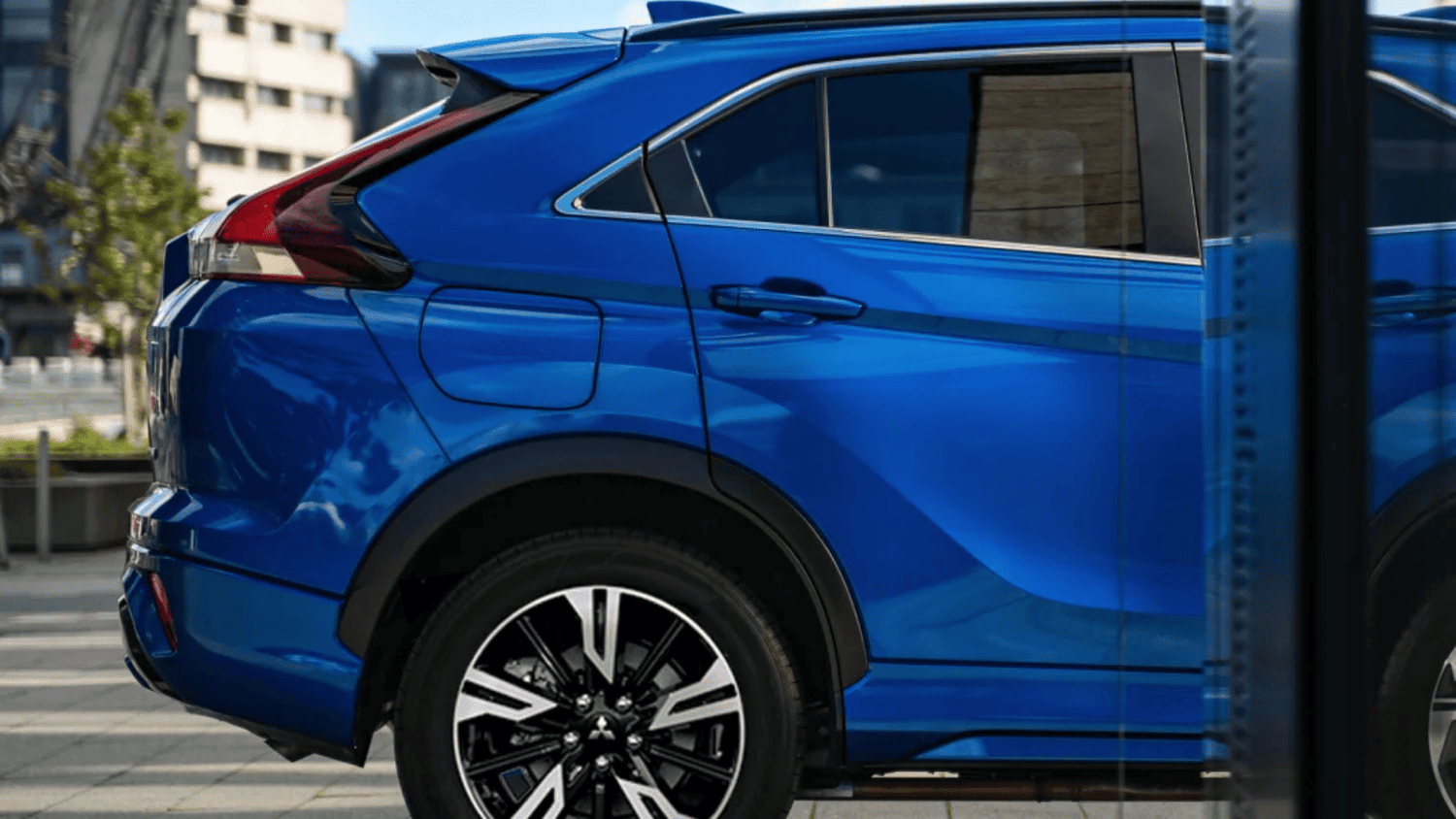 The 2025 Mitsubishi Eclipse Cross in motion on city streets near Lakeland, FL, with LED headlights and aerodynamic front styling.