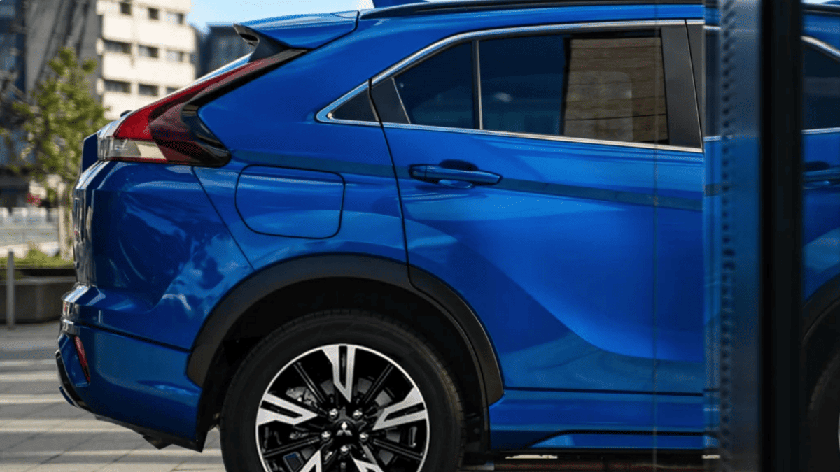 Rear-side view of a blue 2025 Mitsubishi Eclipse Cross trim parked in an urban area near Tampa, FL, showcasing sleek body lines and sporty design.