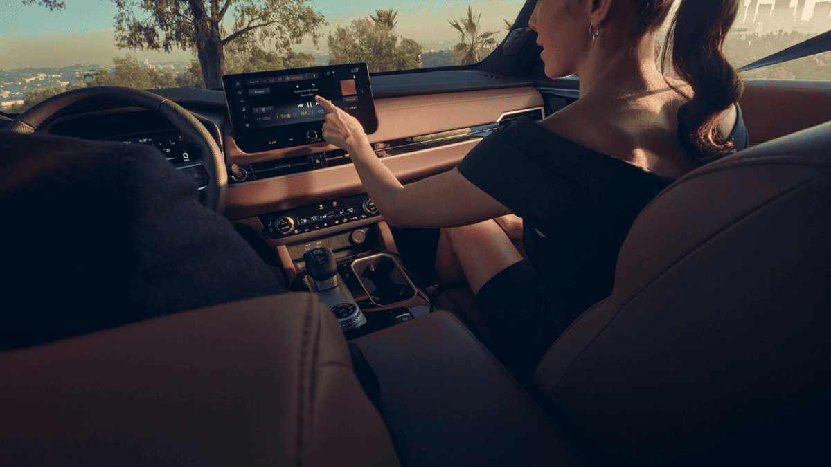 Interior view of the 2025 Mitsubishi Outlander near Riverview, FL, showing a woman reaching for the center touchscreen display, highlighting the SUV’s intuitive tech interface and comfortable layout.