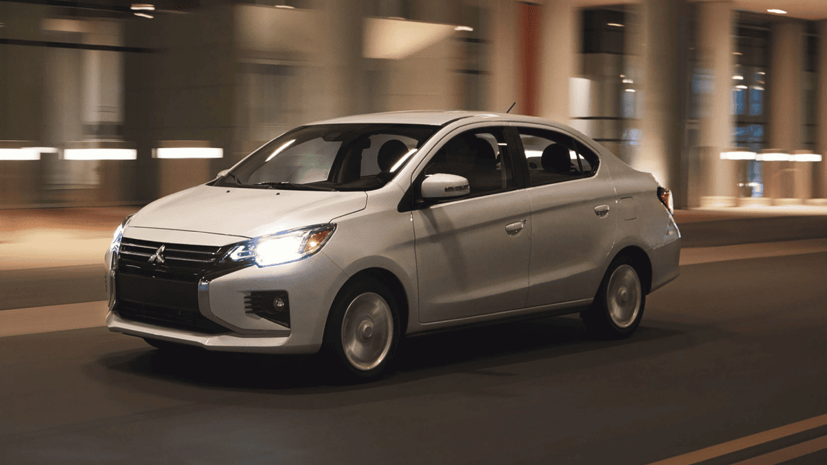 Side view of a white 2024 Mitsubishi Mirage G4 driving at night, demonstrating its efficient performance and sleek sedan silhouette in motion.
