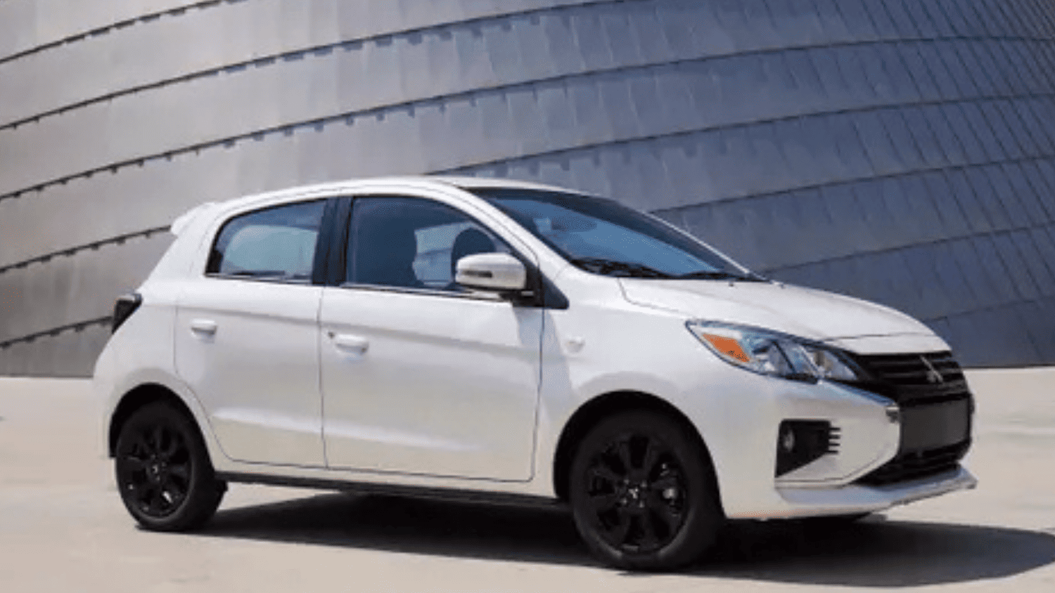 White 2024 Mitsubishi Mirage hatchback parked near a modern architectural backdrop close to Lakeland, FL, highlighting its compact build.