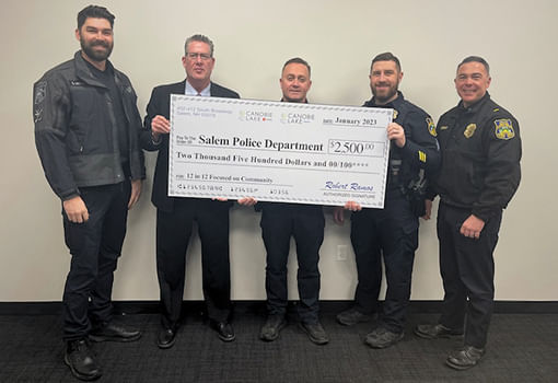 Oficiales de policía sostienen con orgullo un cheque de $2,500, celebrando una donación al Departamento de Policía de Salem NH para 2023.