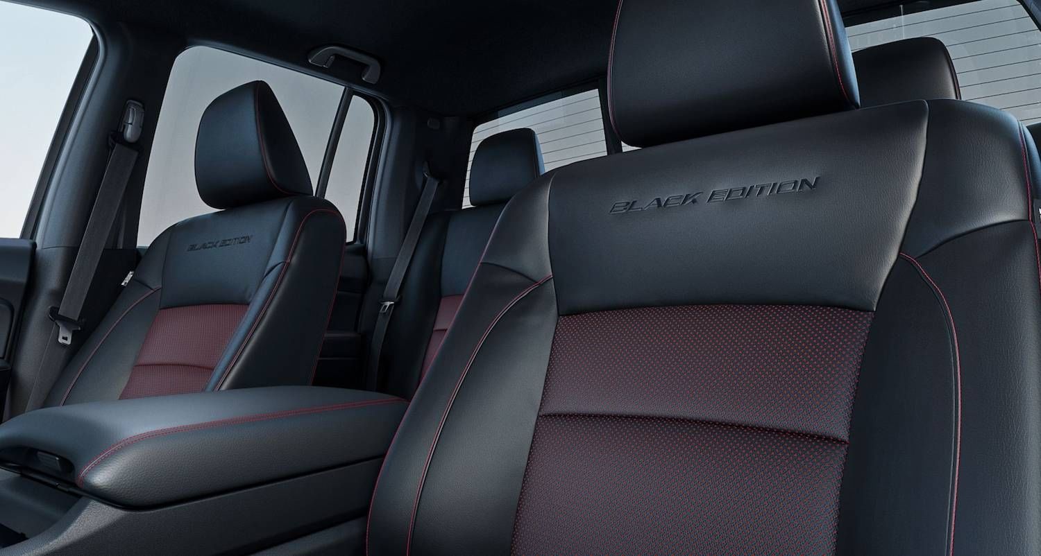 La Honda Ridgeline Black Edition 2025 con interior de cuero negro y rojo, que muestra los asientos delanteros y el tablero desde la puerta del lado del conductor