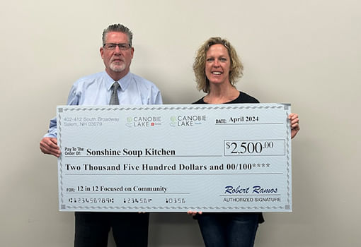 Dos personas sostienen con orgullo un cheque de $2,500, apoyando la misión de Sonshine Soup Kitchen de ayudar a la comunidad.