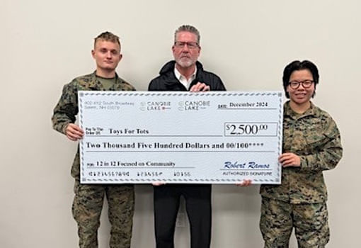 Bob Ramos y dos militares muestran un cheque de $2,500.