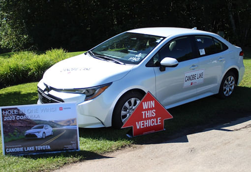 Un automóvil blanco estacionado con un cartel al lado, representando una donación a la Liga de Rescate Animal de Salem.