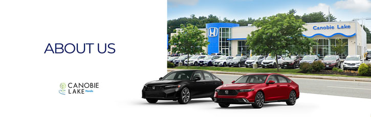Exterior view of a car dealership with a large sign displaying the words "About Us," indicating company information.