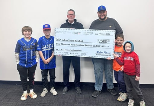 Niños sostienen con orgullo un cheque para Salem New Hampshire Youth Baseball, celebrando el apoyo de Canobie Lake Honda y Toyota