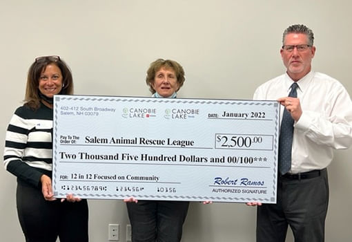 Dos personas muestran con orgullo un cheque grande, simbolizando una donación de $2,500 para apoyar a la Salem Animal Rescue League.