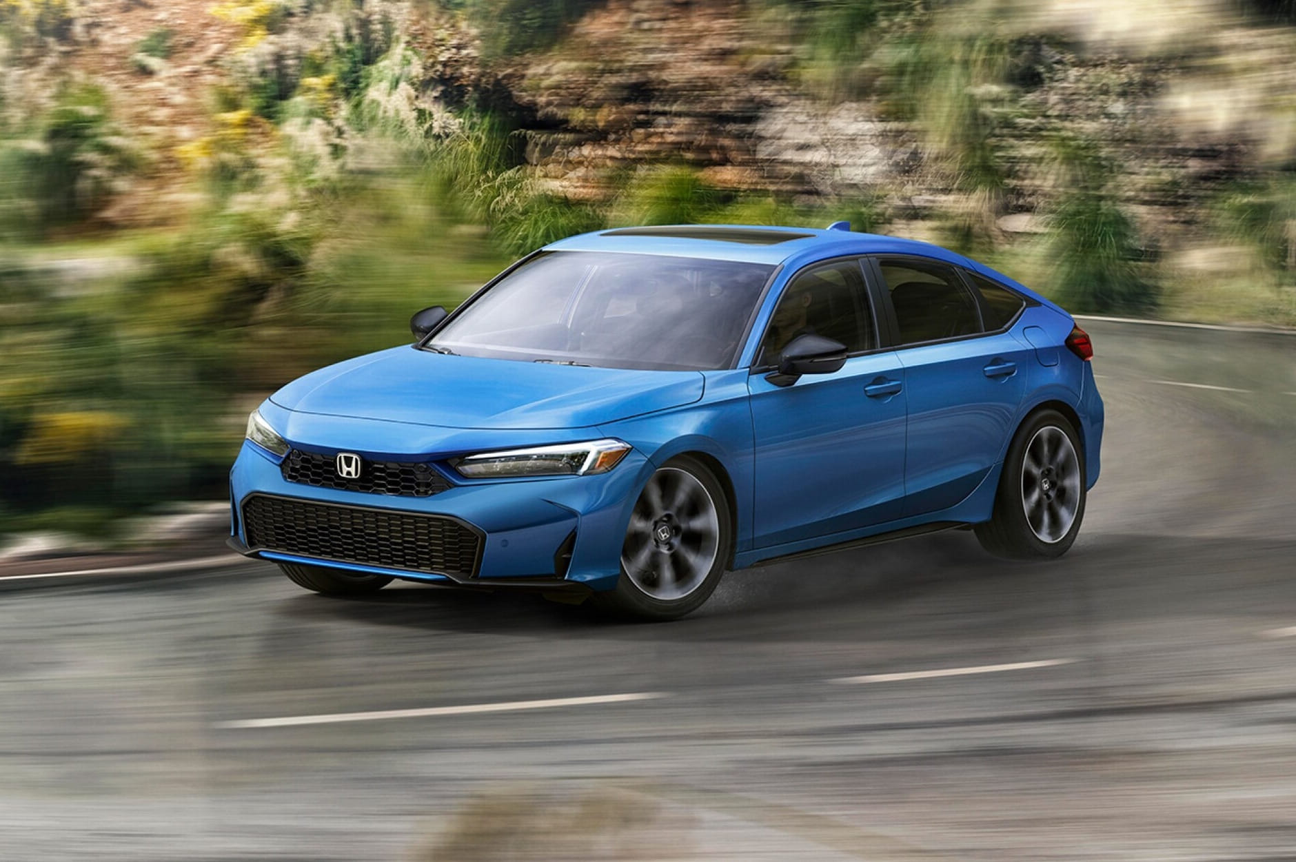 A sleek blue 2026 Honda Civic Hatchback speeds down a winding road. The dynamic motion blur and lush green background emphasize the car's speed and agility.