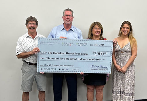 Tres personas sostienen con orgullo un cheque para la Homeland Heroes Foundation, celebrando su asociación con Canobie Lake Honda y Toyota.