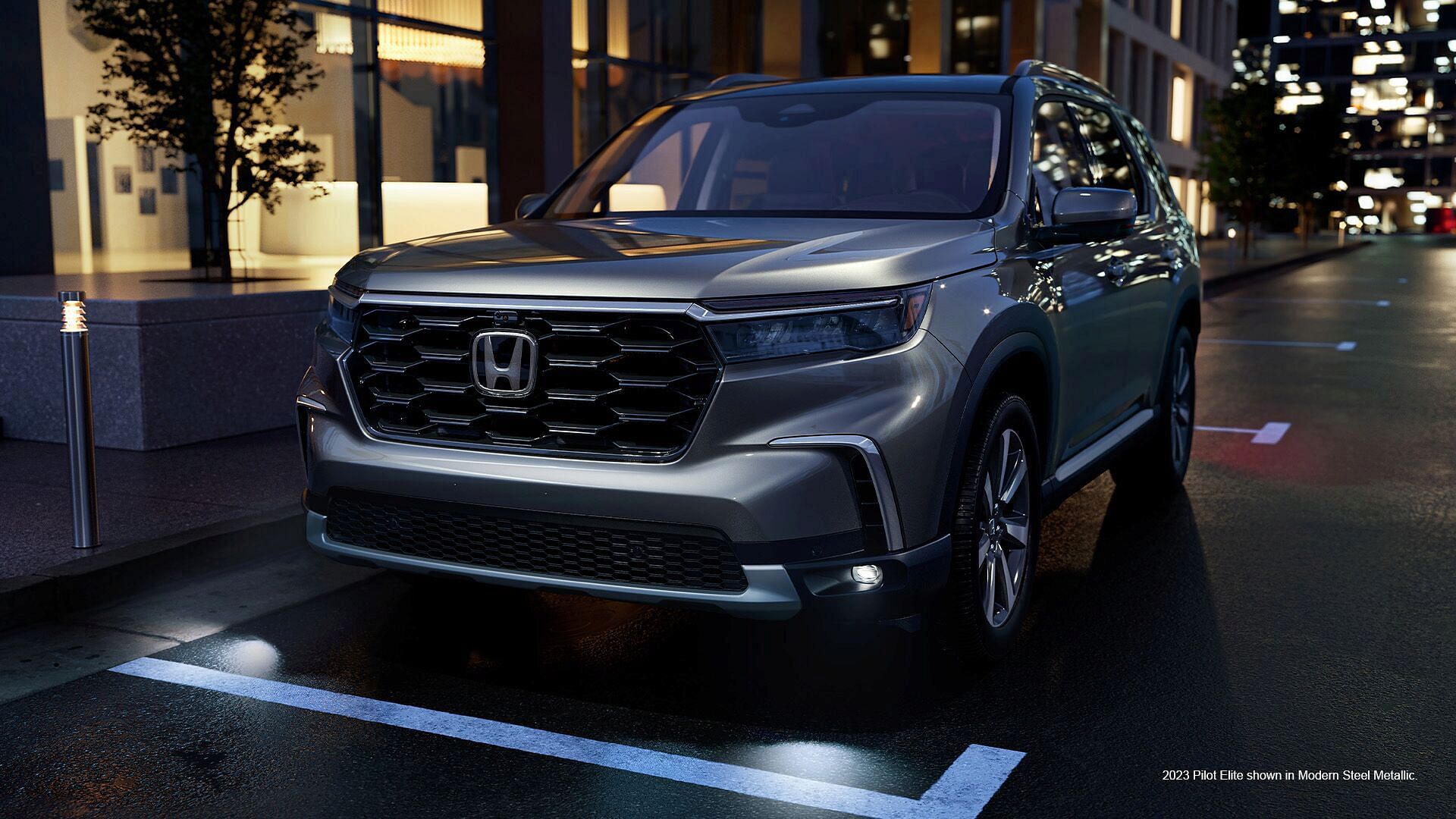 2023 Honda Pilot Elite shown in Modern Steel Metallic standing in the parking at the building