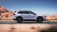 Side of Sport Touring Hybrid Honda CR-V 2023 shown in Platinum White Pearl. Wilderness in the background