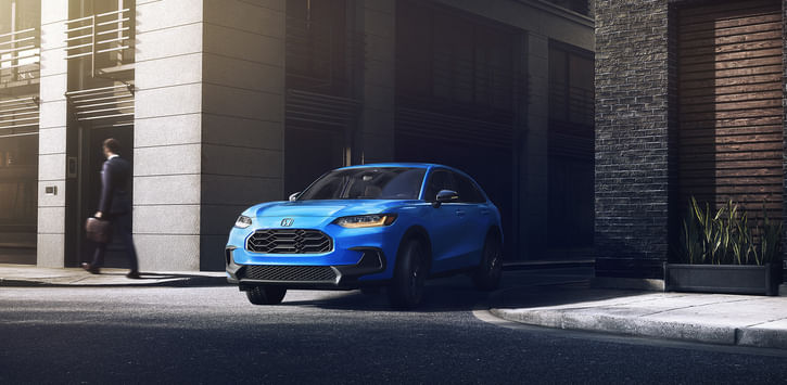 3/4 front view of blue HR-V pulling out of an alleyway in the city.