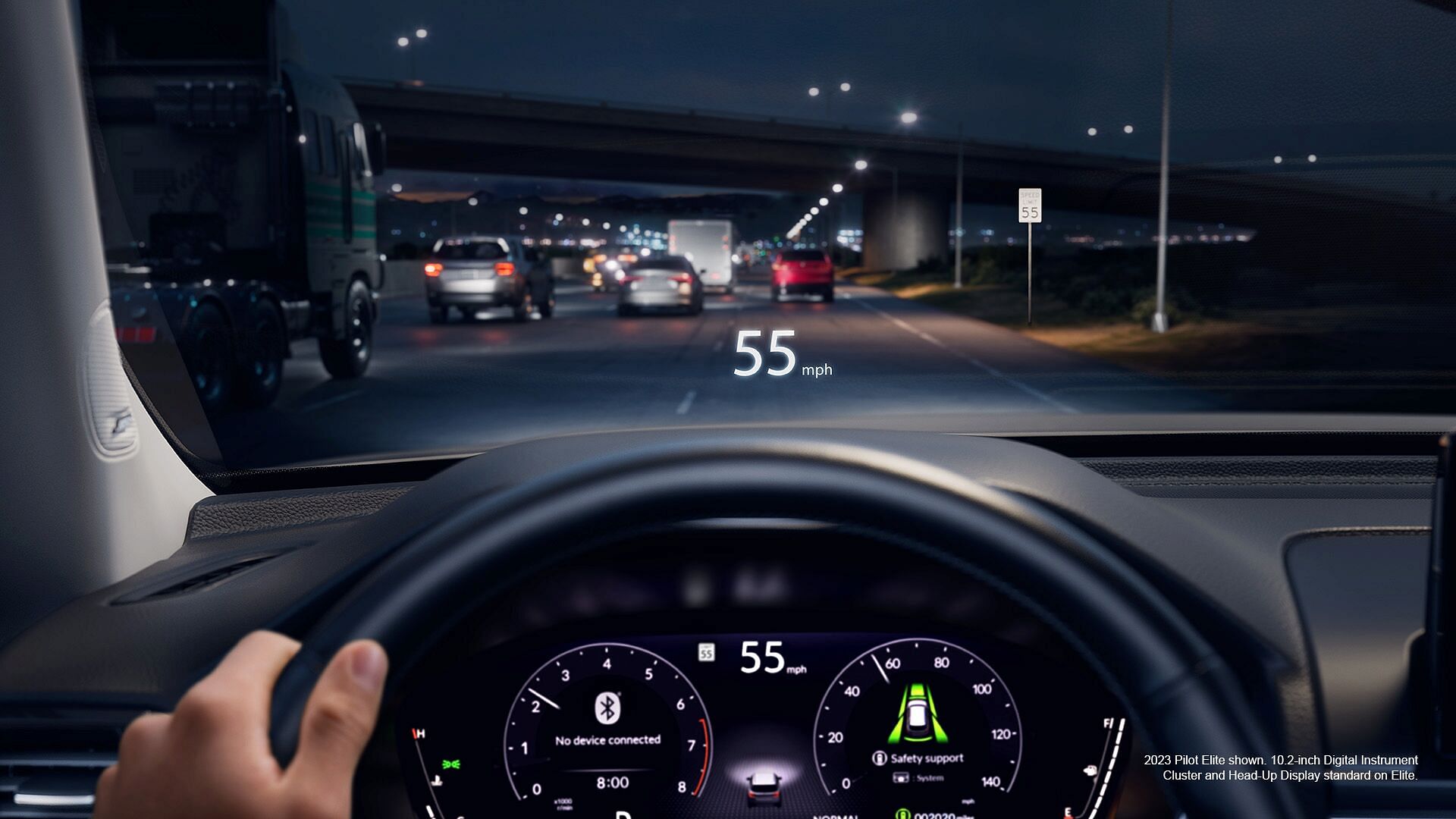 The view from the perspective of a driver driving on the highway at night with the Digital Instrument Cluster and Head-Up Display turned on