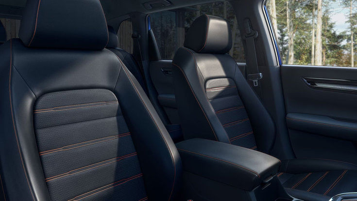 The black leather front seats of a Honda CR-V with orange stitching details.
